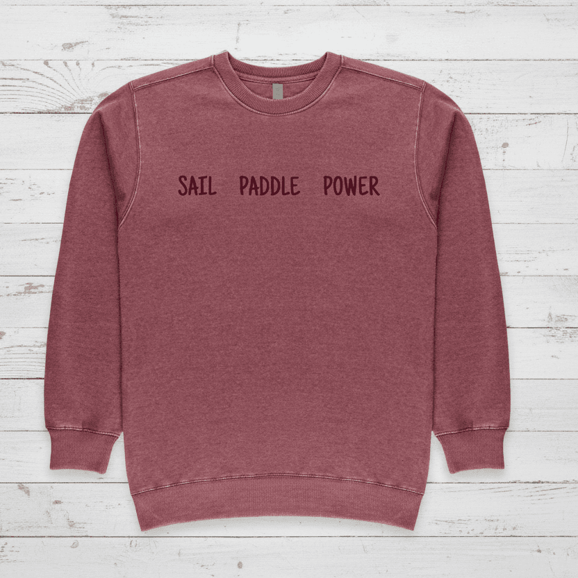 Red sweatshirt with 'SAIL PADDLE POWER' text against a natural background