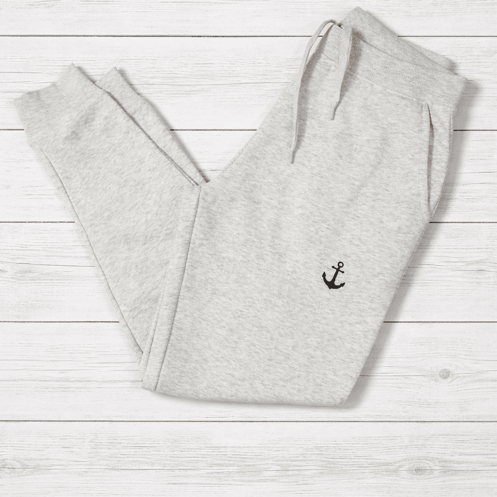 Gray sweatpants with an anchor emblem on a light wooden surface