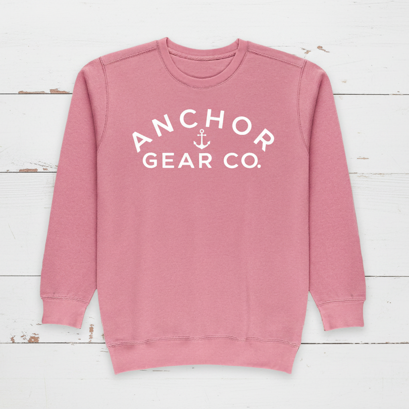 A pink crewneck sweatshirt with 'ANCHOR GEAR CO.' written in white on the front.