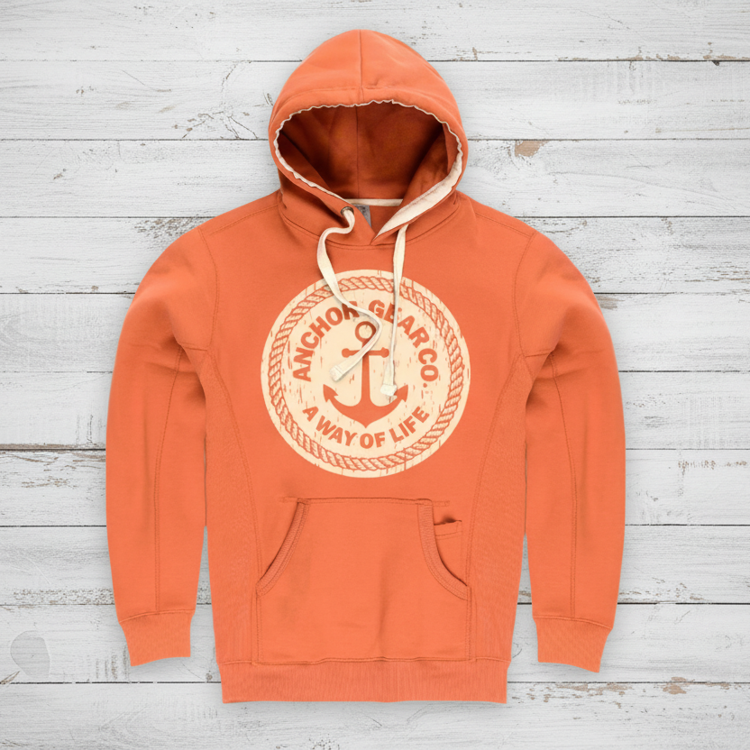 A Texas orange hoodie with a hood, featuring a vintage anchor logo in a larger circle, with a smaller circle inside it containing the text 'A WAY OF LIFE'. The hoodie appears to have a front pocket and is displayed against a wooden background.