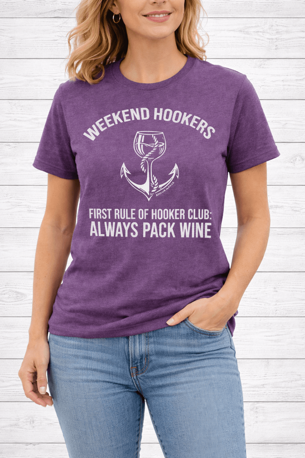 Person wearing a purple t-shirt with humorous text design against a white wooden background