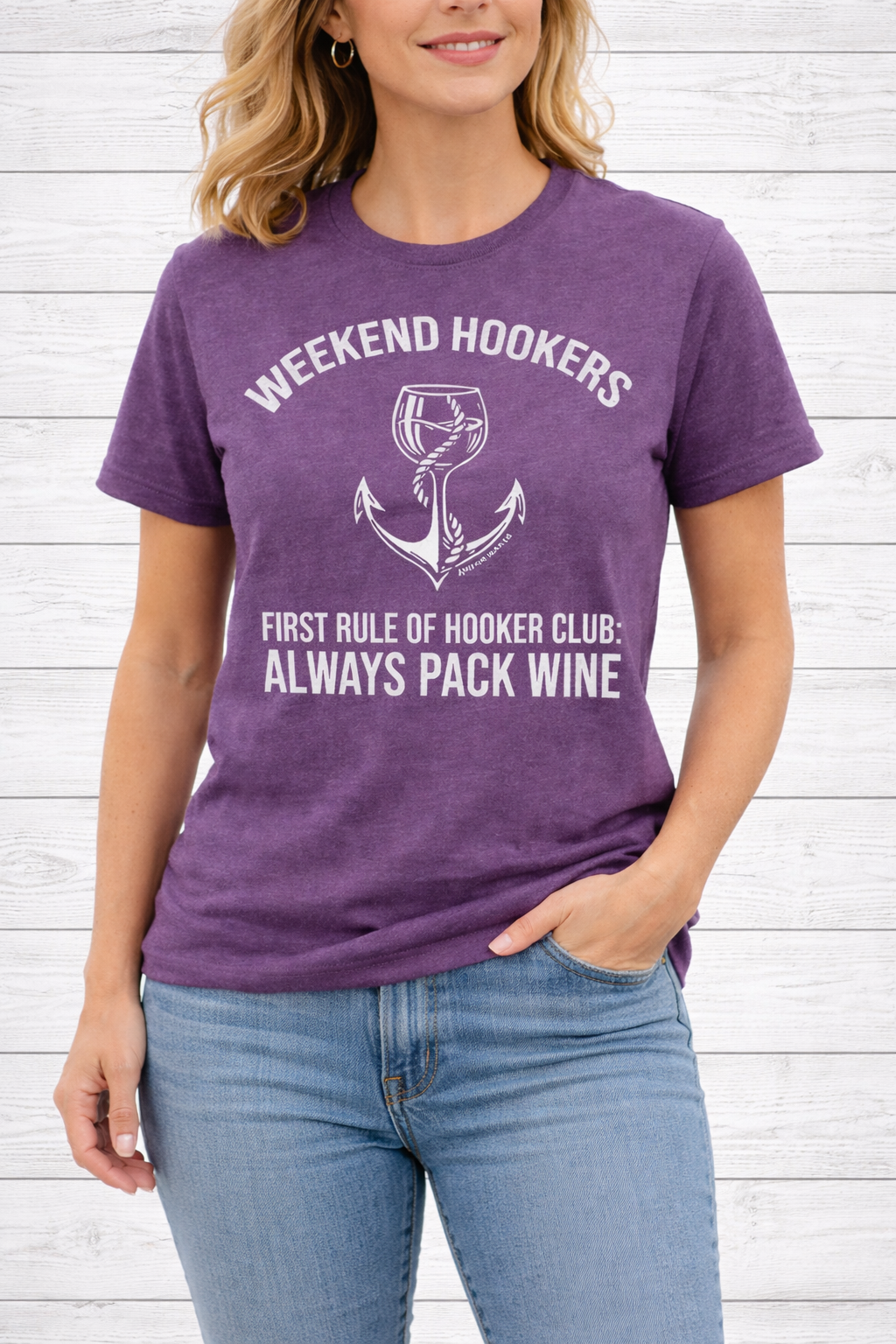 Person wearing a purple t-shirt with humorous text design against a white wooden background