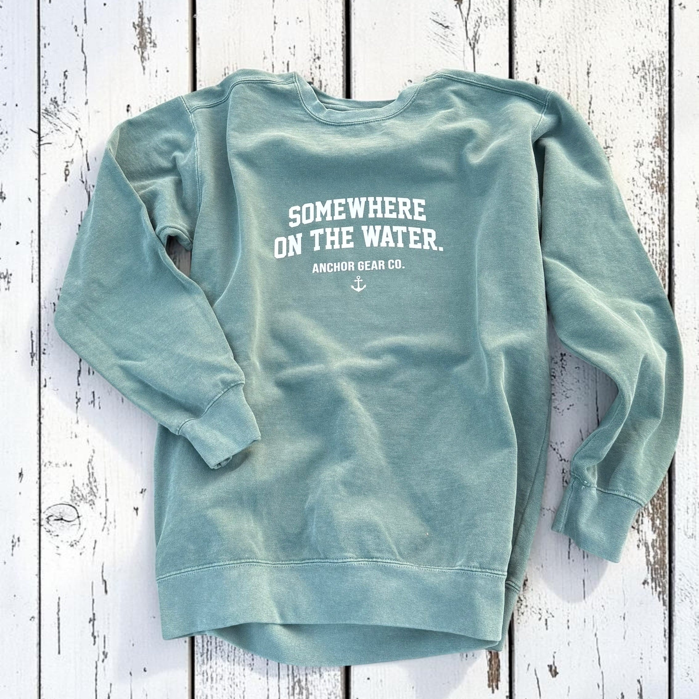 Light blue sweatshirt with text on the back on a wooden surface