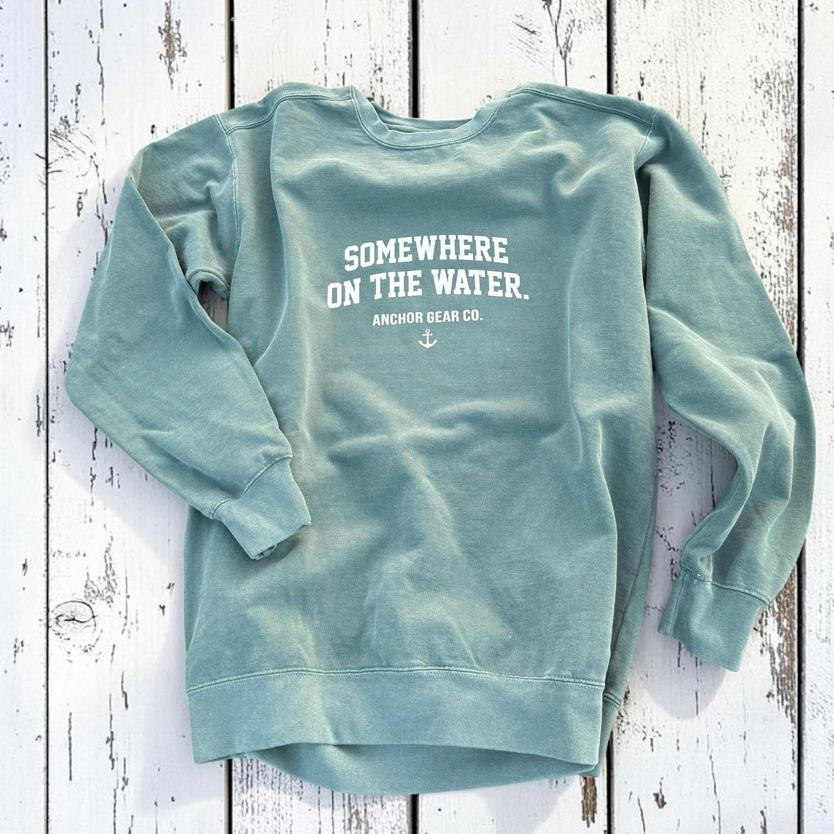 Light blue sweatshirt with text on the back on a wooden surface