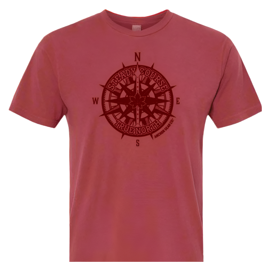 Red t-shirt with a compass design against a scenic background of trees and water.