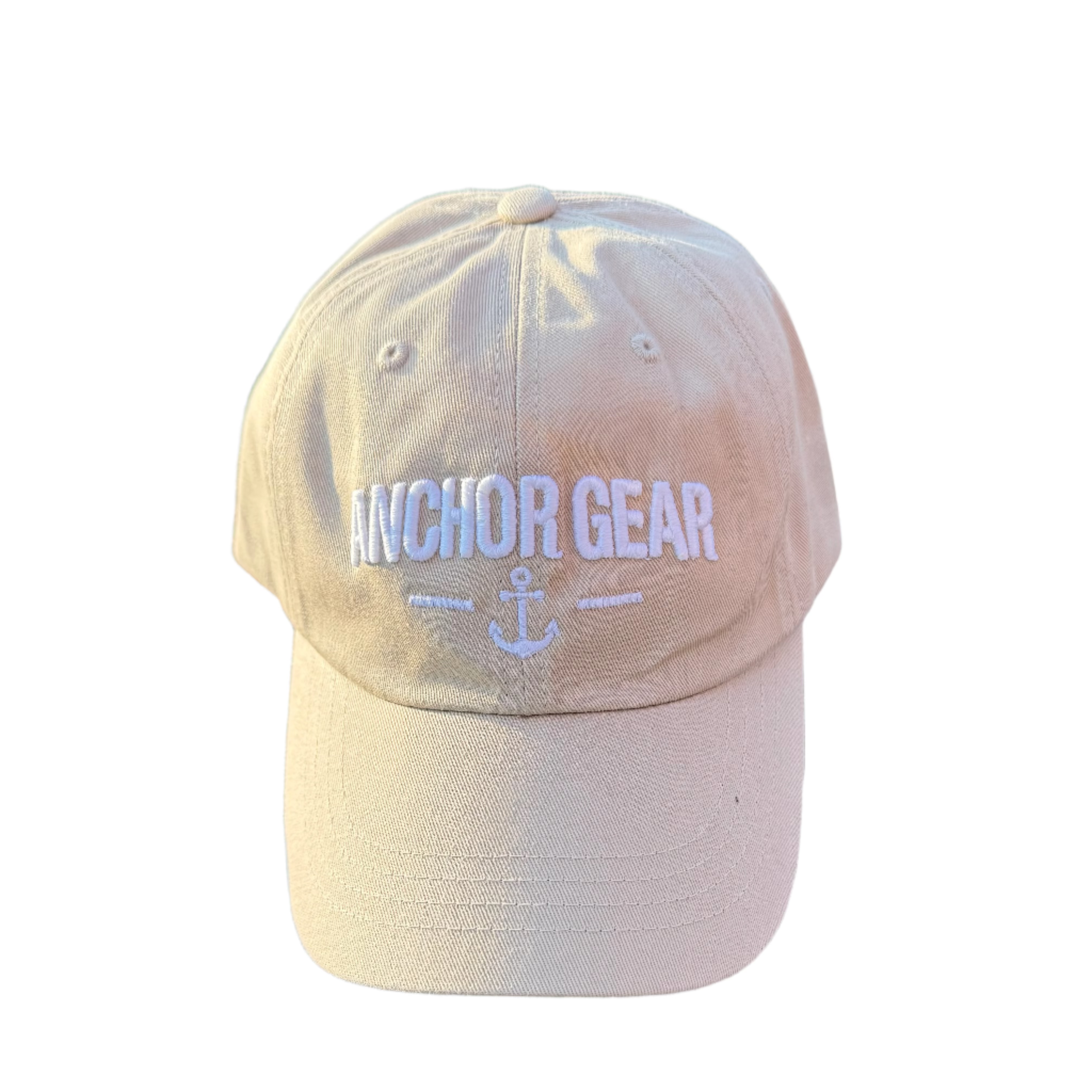 Beige cap with 'Anchor Gear' logo on a rock with greenery in the background