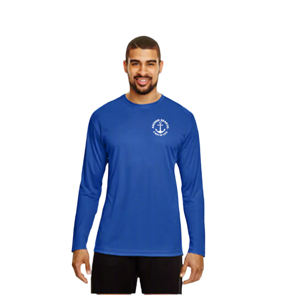 A man standing by a body of water wearing a blue long sleeve UV shirt with a white anchor logo on the chest.