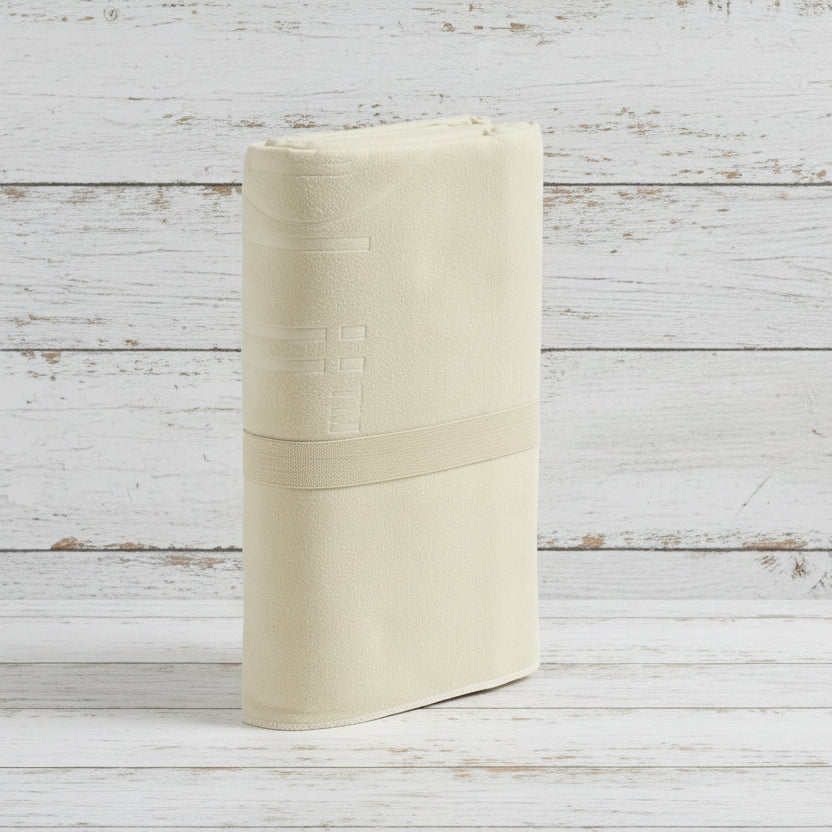 A beige Talii Towel draped over a flat surface with a person standing in front, holding the towel at the top, showing the size and color of the towel.