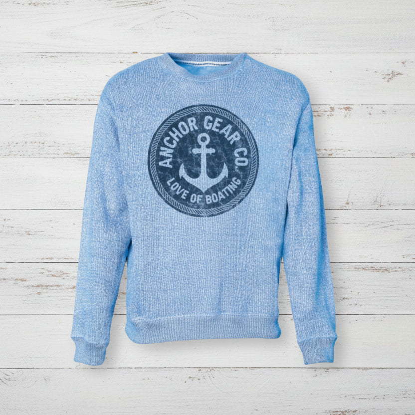 Blue sweatshirt with anchor logo on a wooden surface