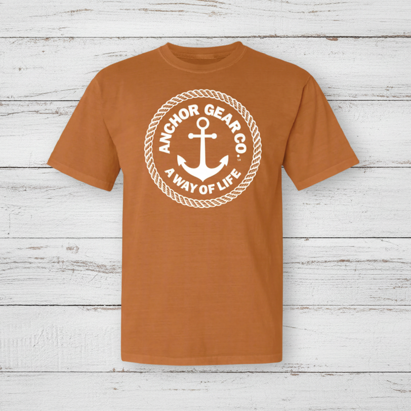 Orange t-shirt with anchor logo and text on a dock by water