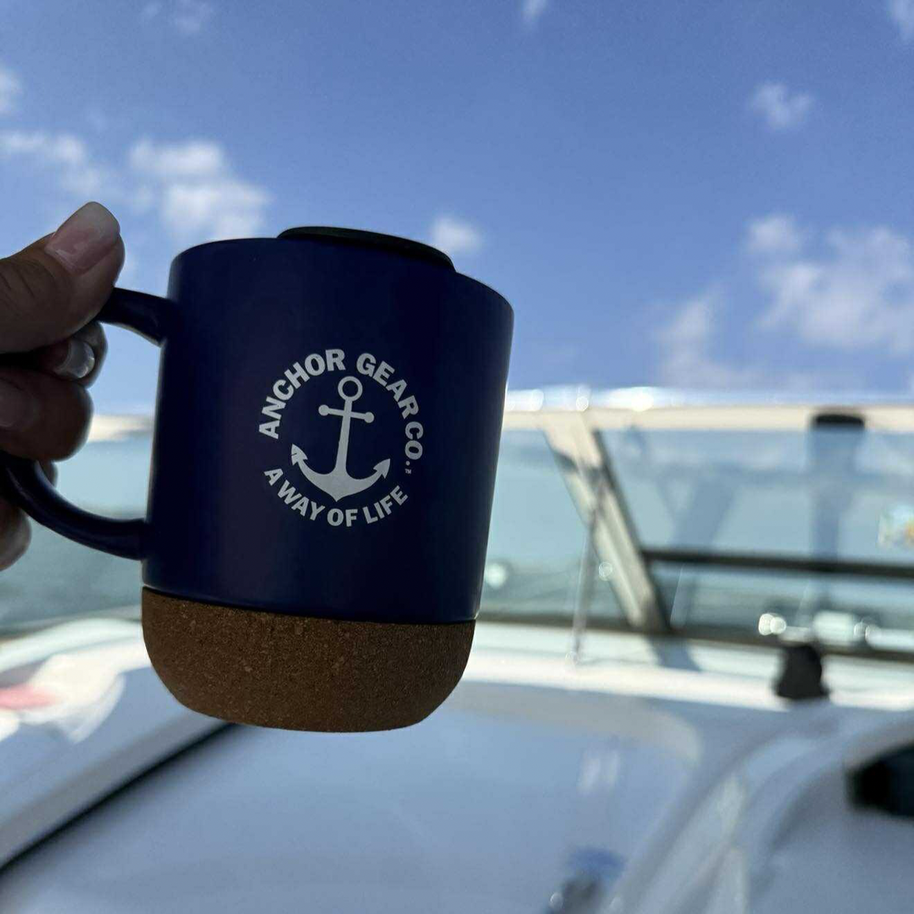 Navy blue mug with cork base held on a boat, featuring 'Anchor Gear Co.' branding.
