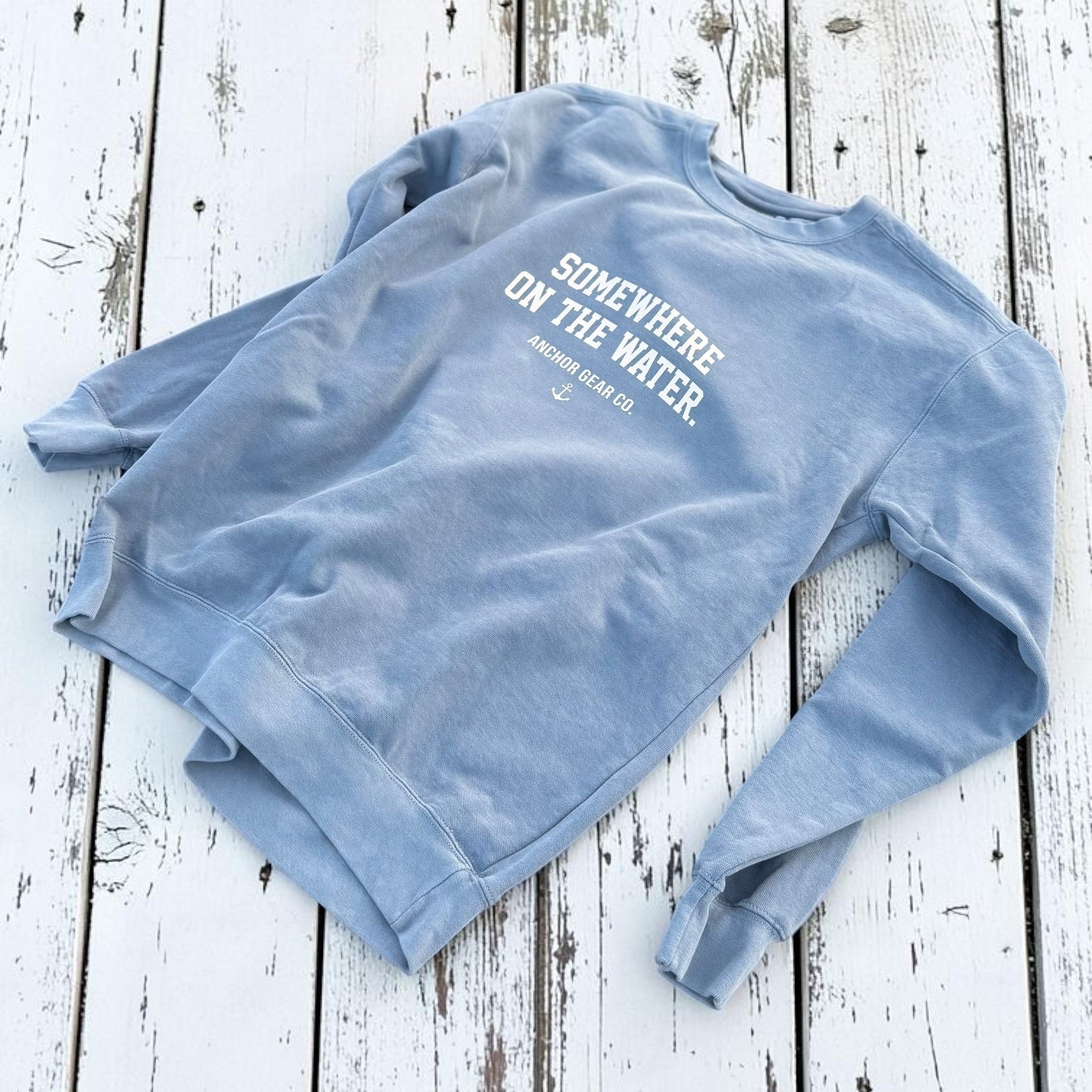 Light blue sweatshirt with text on a wooden surface