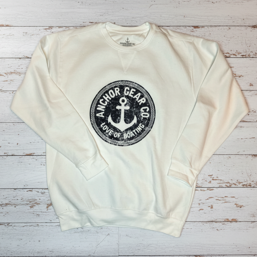 A white and navy crewneck sweatshirt with a bold anchor design on a wooden dock background.