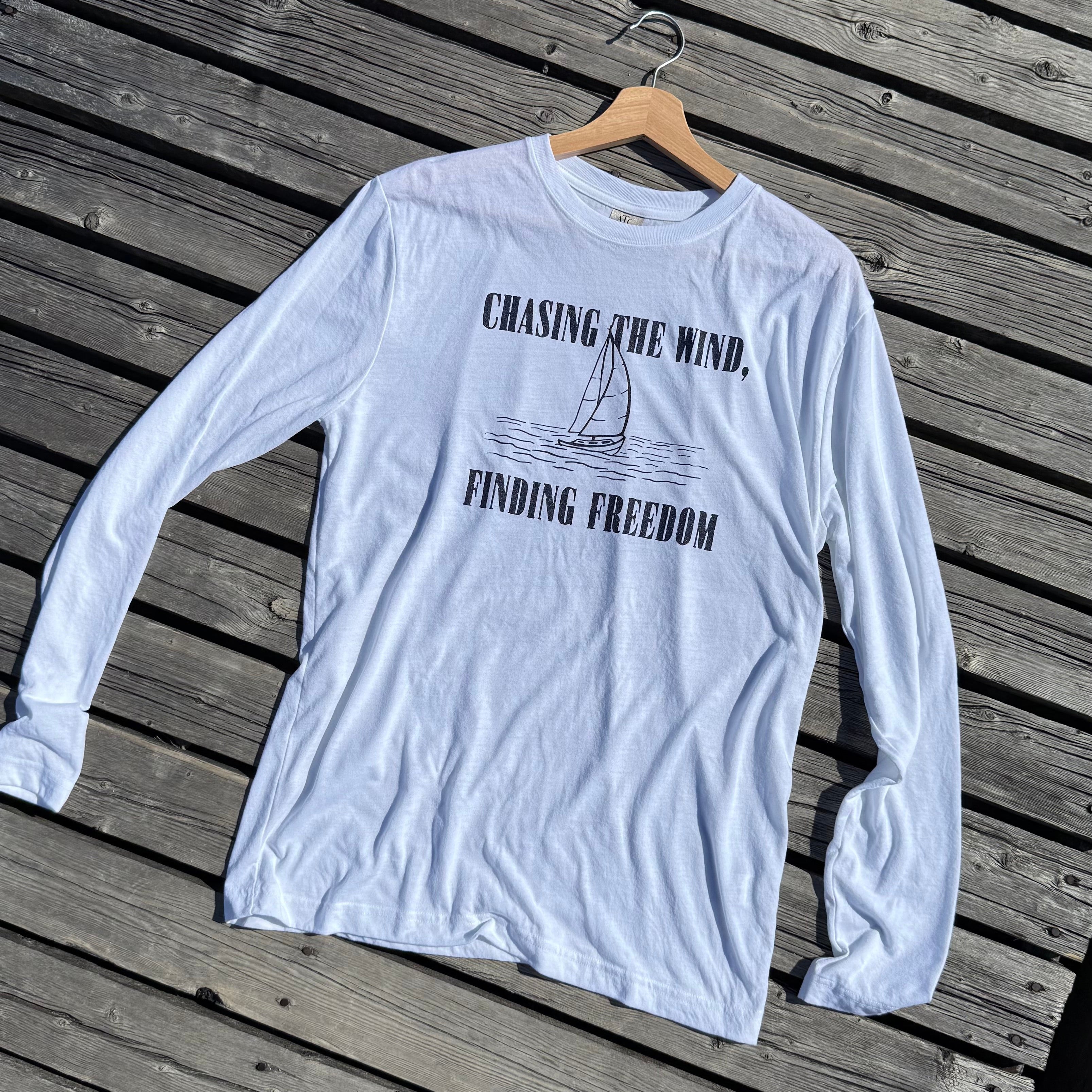 White long-sleeve shirt with text and graphic on a wooden surface