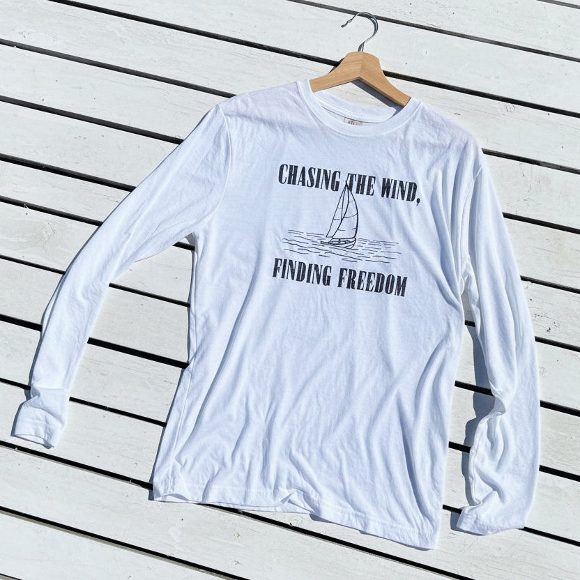 White long-sleeve shirt with text and graphic on a wooden surface
