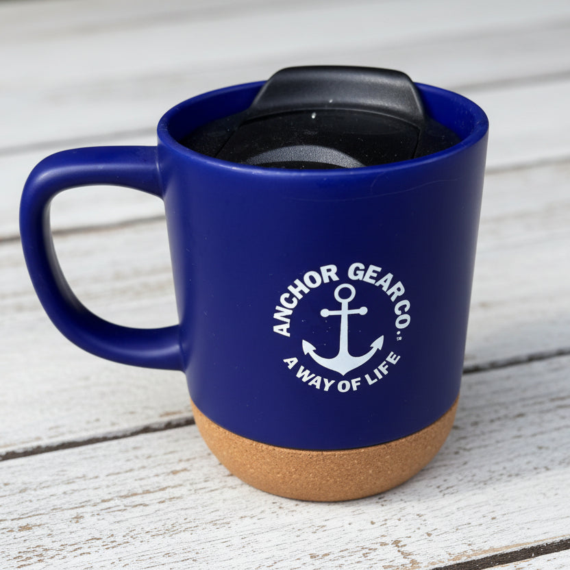 A navy-colored ceramic mug with a cork bottom and a black secure sip lid, featuring the Anchor Gear Co. logo.