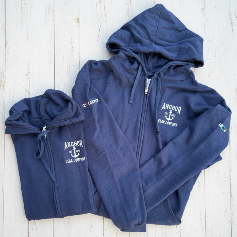 Two navy blue hoodies with a visible brand logo on a wooden surface