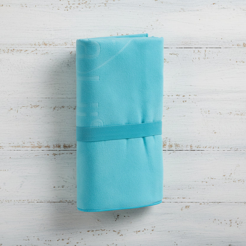 A tiffany Talii Towel draped over a flat surface with a person standing in front, holding the towel at the top, showing the size and colour of the towel.