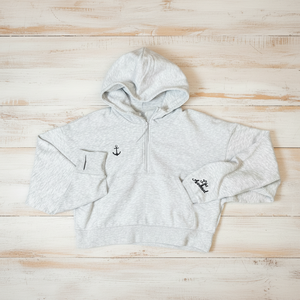 White hoodie with anchor design on a light blue wooden surface